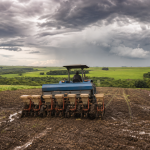 Máquina agrícola trabalha em lavoura úmida durante o início da safra brasileira de grãos.