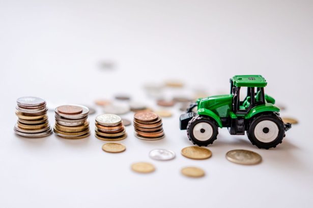 Trator verde em miniatura ao lado de pilhas de moedas, em uma composição ilustrativa sobre financiamento agrícola.
